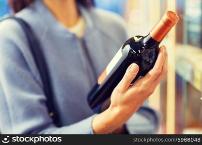 sale, shopping, consumerism and people concept - happy young woman choosing and buying wine in market or liquor store