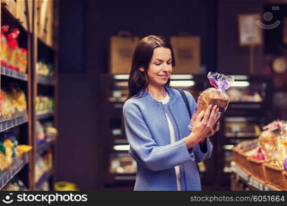sale, shopping, consumerism and people concept - happy young woman choosing and reading label on bread in market