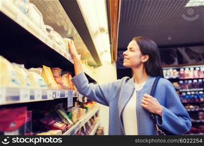 sale, shopping, consumerism and people concept - happy young woman choosing and buying food in market