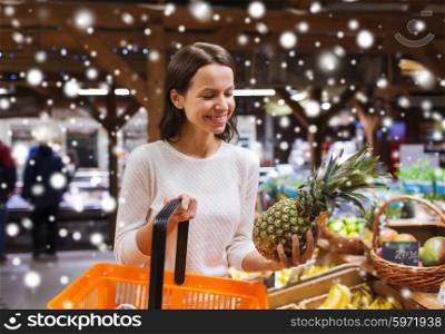 sale, shopping, consumerism and people concept - happy young woman with food basket in market or grocery store over snow effect