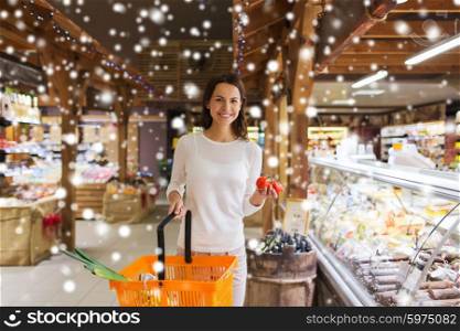 sale, shopping, consumerism and people concept - happy young woman with food basket and tomatoes in market over snow effect