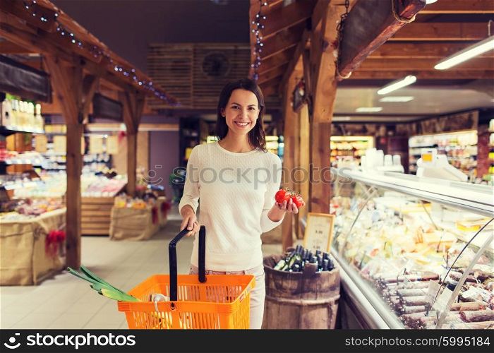 sale, shopping, consumerism and people concept - happy young woman with food basket and tomatoes in market