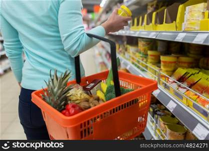 sale, shopping, consumerism and people concept - woman with food basket and jar at grocery store or supermarket