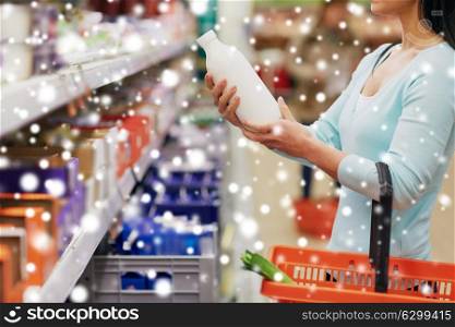 sale, shopping, consumerism and people concept - young female customer holding milk bottle at grocery store or supermarket over snow. woman with milk bottle at grocery or supermarket