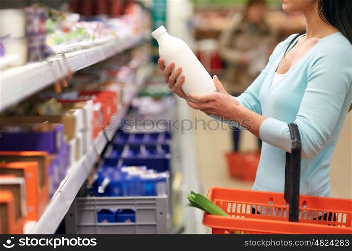sale, shopping, consumerism and people concept - young woman holding milk bottle at grocery store or supermarket