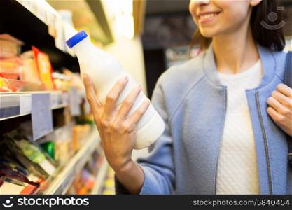 sale, shopping, consumerism, food and people concept - close up of happy young woman holding milk bottle in market