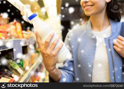 sale, shopping, consumerism, food and people concept - close up of happy young woman holding milk bottle in market or grocery store over snow effect