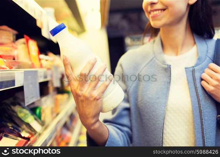 sale, shopping, consumerism, food and people concept - close up of happy young woman holding milk bottle in market