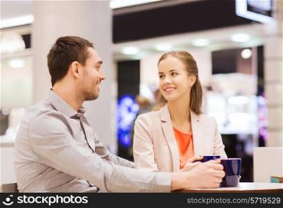 sale, shopping, consumerism, leisure and people concept - happy couple with shopping bags drinking coffee in mall