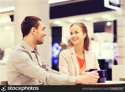 sale, shopping, consumerism, leisure and people concept - happy couple with shopping bags drinking coffee in mall