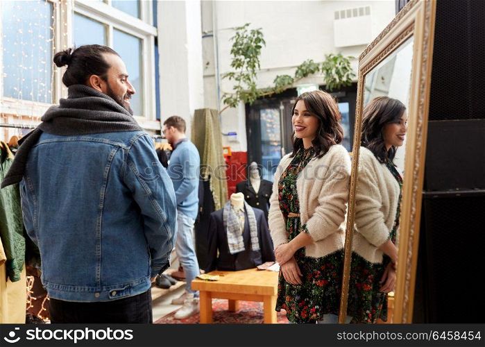 sale, shopping, fashion and people concept - couple choosing clothes at vintage clothing store. couple choosing clothes at vintage clothing store