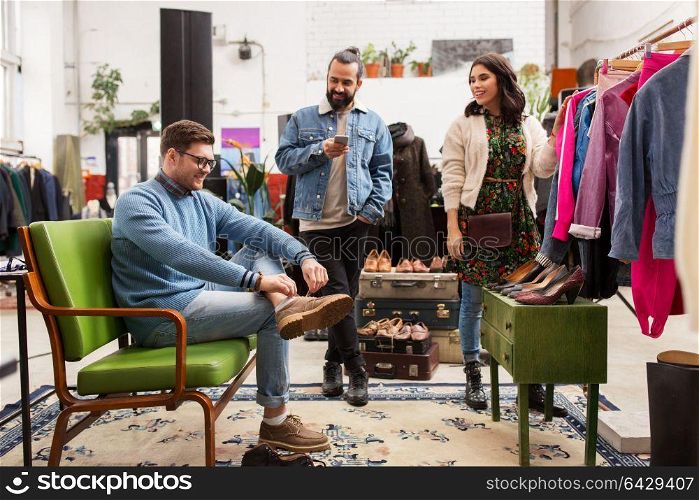 sale, shopping, fashion and people concept - friends choosing clothes and footwear at vintage clothing store. friends choosing clothes at vintage clothing store