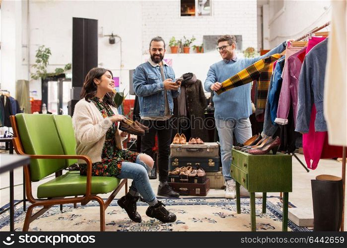 sale, shopping, fashion and people concept - friends choosing clothes and footwear at vintage clothing store. friends choosing clothes at vintage clothing store