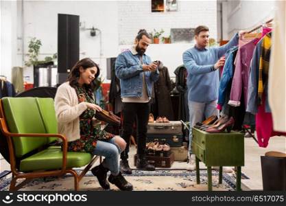 sale, shopping, fashion and people concept - friends choosing clothes and footwear at vintage clothing store. friends choosing clothes at vintage clothing store. friends choosing clothes at vintage clothing store