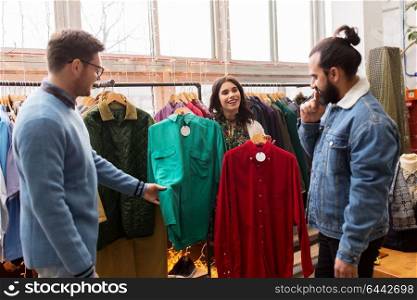 sale, shopping, fashion and people concept - friends choosing clothes at vintage clothing store. friends choosing clothes at vintage clothing store