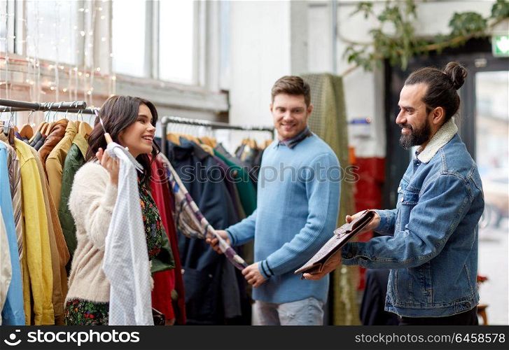 sale, shopping, fashion and people concept - friends choosing clothes at vintage clothing store. friends choosing clothes at vintage clothing store