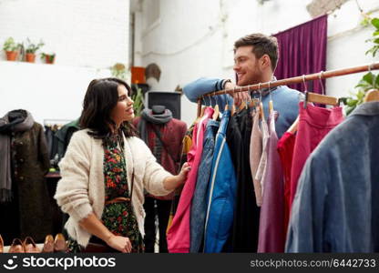 sale, shopping, fashion and people concept - happy couple at vintage clothing store hanger. happy couple at vintage clothing store hanger