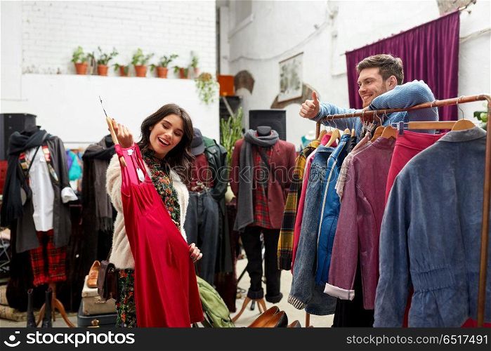 sale, shopping, fashion and people concept - happy couple choosing clothes at vintage clothing store and showing thumbs up. couple choosing clothes at vintage clothing store. couple choosing clothes at vintage clothing store
