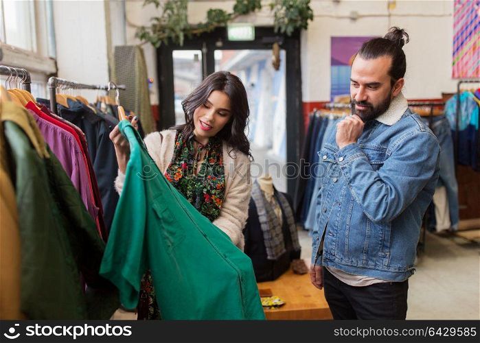 sale, shopping, fashion and people concept - happy couple choosing clothes at vintage clothing store. couple choosing clothes at vintage clothing store
