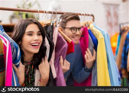 sale, shopping, fashion and people concept - happy couple having fun at vintage clothing store hanger. happy couple having fun at vintage clothing store
