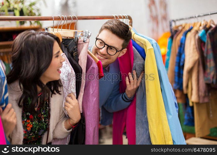 sale, shopping, fashion and people concept - happy couple having fun at vintage clothing store hanger. happy couple having fun at vintage clothing store. happy couple having fun at vintage clothing store