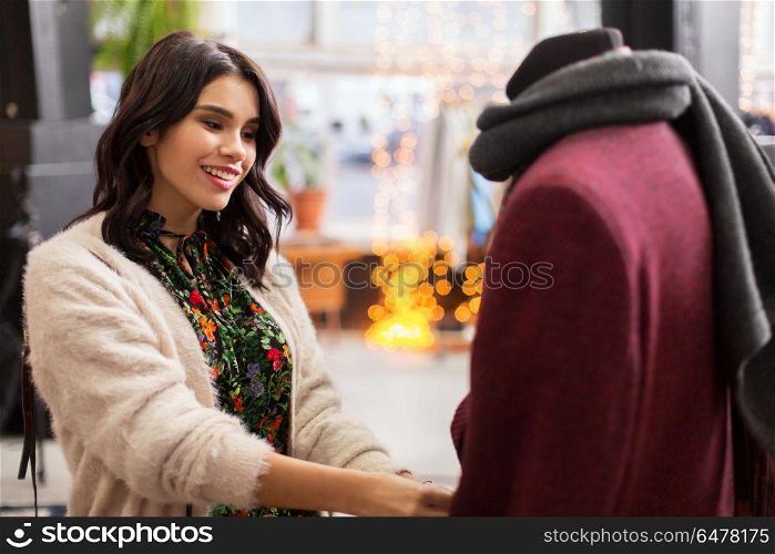 sale, shopping, fashion and people concept - happy young woman choosing clothes at clothing store. happy woman choosing clothes at clothing store. happy woman choosing clothes at clothing store