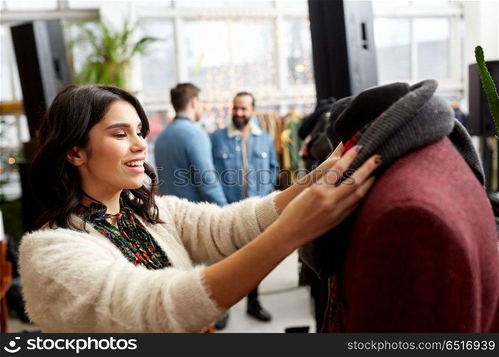 sale, shopping, fashion and people concept - happy young woman choosing clothes at clothing store. happy woman choosing clothes at clothing store. happy woman choosing clothes at clothing store