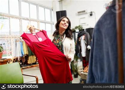 sale, shopping, fashion and people concept - happy young woman choosing dress at clothing store. happy woman choosing dress at clothing store. happy woman choosing dress at clothing store