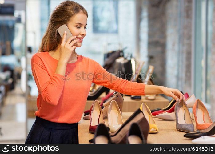 sale, shopping, fashion and people concept - happy young woman choosing shoes at store and calling on smartphone. young woman calling on smartphone at shoe store