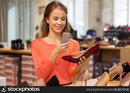 sale, shopping, fashion and people concept - happy young woman taking photo by smartphone at shoe store. woman taking photo by smartphone at shoe store