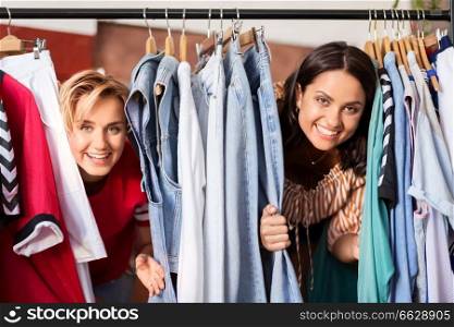 sale, shopping, fashion and people concept - happy young women or female friends having fun at vintage clothing store hanger. women having fun at vintage clothing store hanger