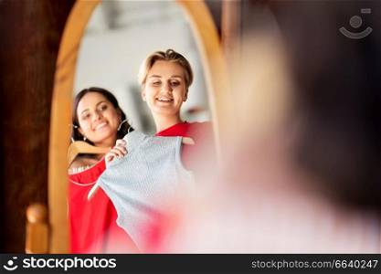 sale, shopping, fashion and people concept - mirror reflection of happy young women choosing clothes together at vintage clothing store. women choosing clothes at vintage clothing store