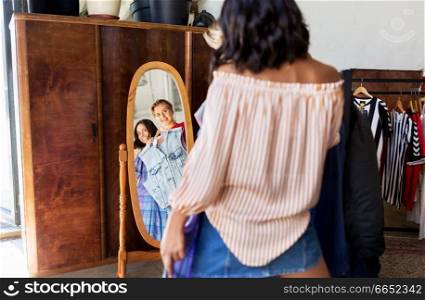 sale, shopping, fashion and people concept - mirror reflection of happy young women choosing clothes together at vintage clothing store. women choosing clothes at vintage clothing store