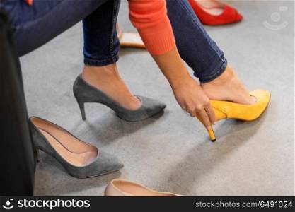 sale, shopping, fashion and people concept - young woman choosing high-heeled peep toe shoes at store. young woman trying high-heeled shoes at store. young woman trying high-heeled shoes at store