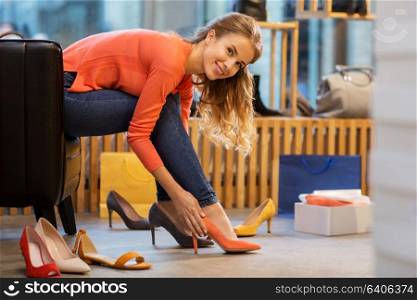 sale, shopping, fashion and people concept - young woman choosing high heeled shoes at store. young woman trying high heeled shoes at store