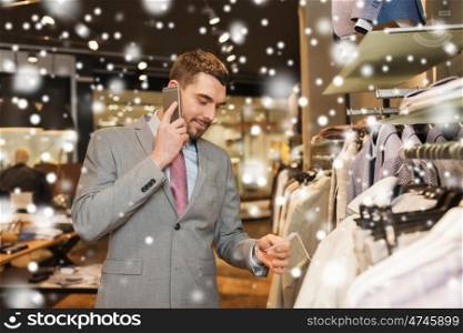sale, shopping, fashion, communication and people concept - happy young man or businessman calling on smartphone and choosing clothes at clothing store over snow