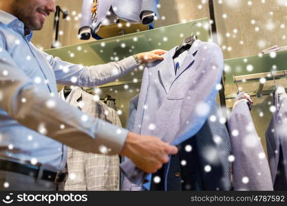 sale, shopping, fashion, style and people concept - close up of man choosing jacket at clothing store over snow