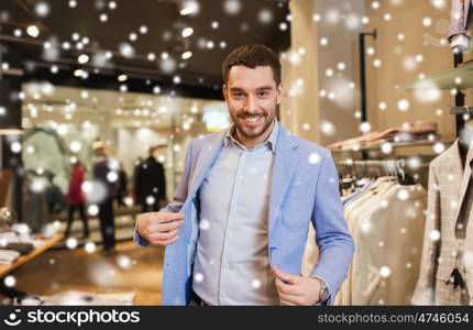 sale, shopping, fashion, style and people concept - elegant young man choosing and trying jacket on in mall or clothing store over snow