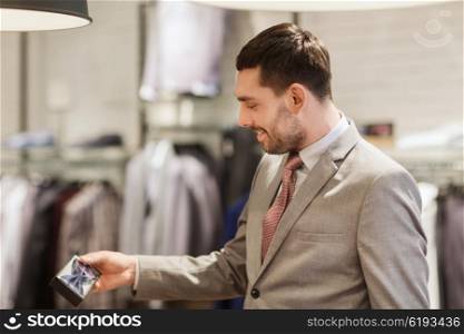 sale, shopping, fashion, style and people concept - elegant young man in suit choosing bow-tie in mall or clothing store