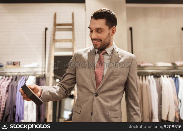 sale, shopping, fashion, style and people concept - elegant young man or businessman in suit holding little box in mall or clothing store