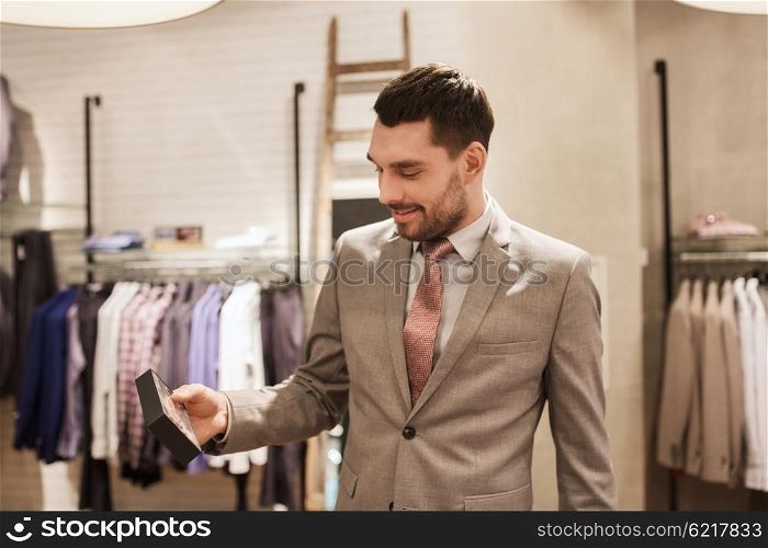 sale, shopping, fashion, style and people concept - elegant young man or businessman in suit choosing bow-tie in mall or clothing store