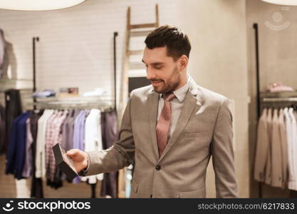 sale, shopping, fashion, style and people concept - elegant young man or businessman in suit choosing bow-tie in mall or clothing store