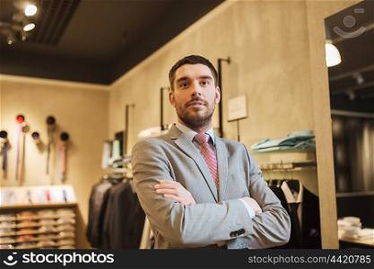 sale, shopping, fashion, style and people concept - happy young man or businessman in suit and tie at clothing store
