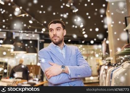 sale, shopping, fashion, style and people concept - happy young man or businessman in jacket and wristwatch at clothing store over snow