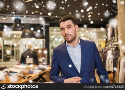 sale, shopping, fashion, style and people concept - young handsome man in jacket at clothing store over snow