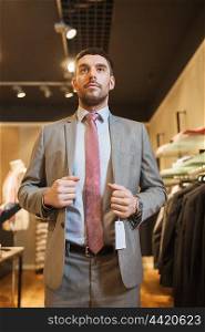 sale, shopping, fashion, style and people concept - young man or businessman trying suit at clothing store