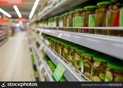 sale, shopping, food and consumerism concept - jars of pickles on grocery or supermarket shelves