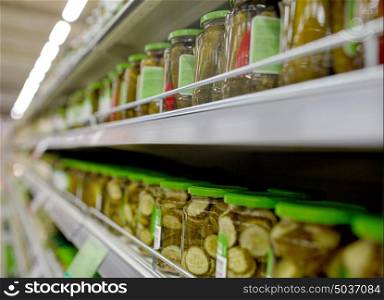 sale, shopping, food and consumerism concept - jars of pickles on grocery or supermarket shelves. jars of pickles on grocery or supermarket shelves