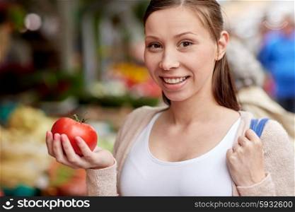 sale, shopping, food and people concept - happy woman holding tomato at street market