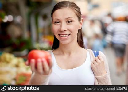 sale, shopping, food and people concept - happy woman holding tomato at street market